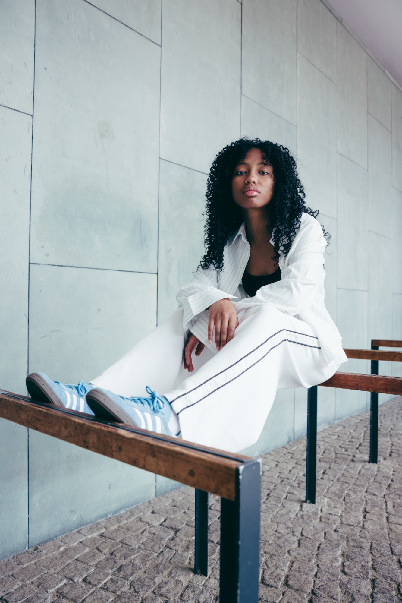 Adidas Originals Court Study – Sportives Layering aus V-Neck-Cricket-Knit und weiter Trackpants auf Steinbank sitzend von Kürsat Gürbüz