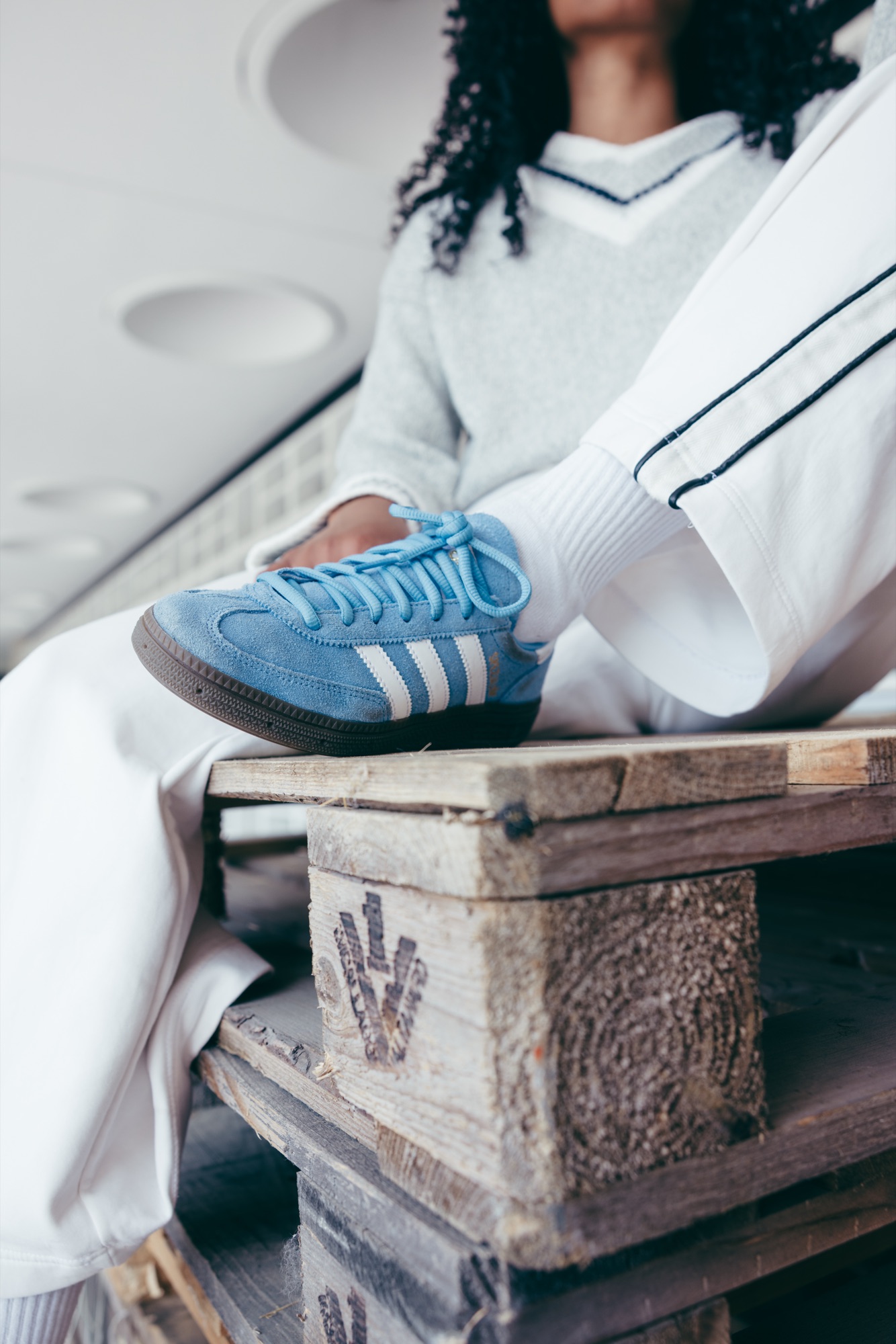 Adidas Originals Court Study – Entspannte Pose auf Holzkonstruktion mit weißer Adidas Trainingshose mit Seitenstreifen von Kürsat Gürbüz