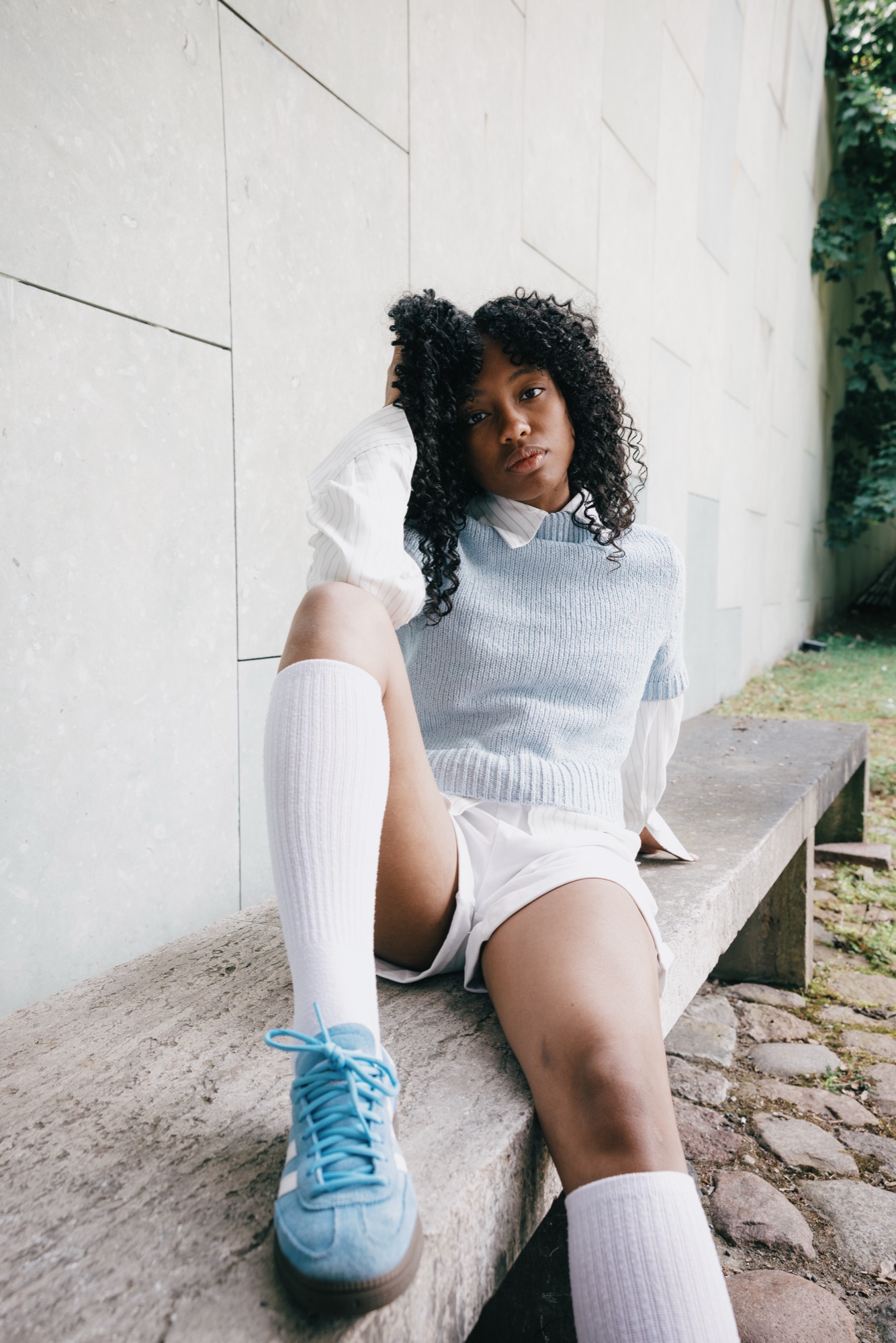 Adidas Originals Court Study – Sitzend auf Steinbank mit fokussiertem Blick und blauem Wildlederschuh im Vordergrund von Kürsat Gürbüz