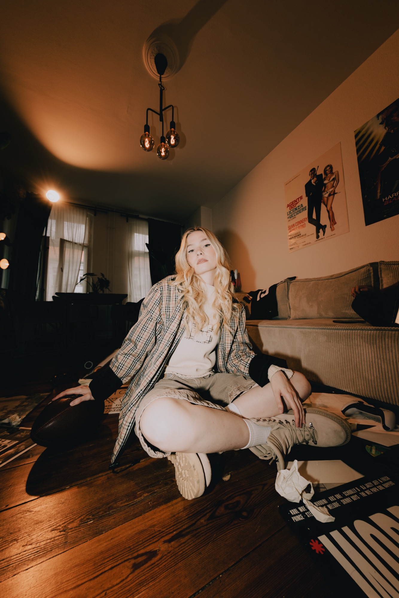 Esther Graf – Halbtotale im Wohnzimmer-Set mit Vintage-Postern und warmem Raumlicht von Kürsat Gürbüz