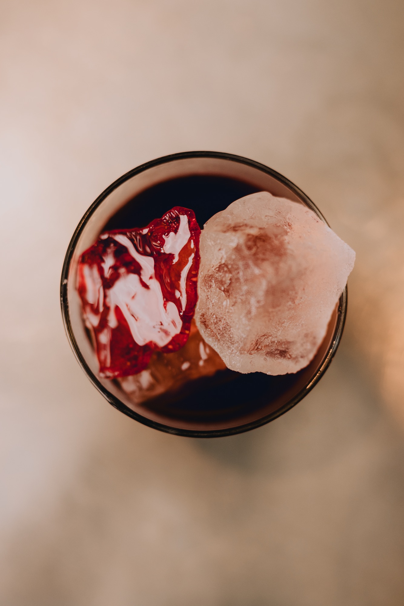 Goldies Bar – Roter Signature Cocktail mit Klareis auf spiegelndem Edelstahltresen im warmen Bar-Ambiente von Kürsat Gürbüz