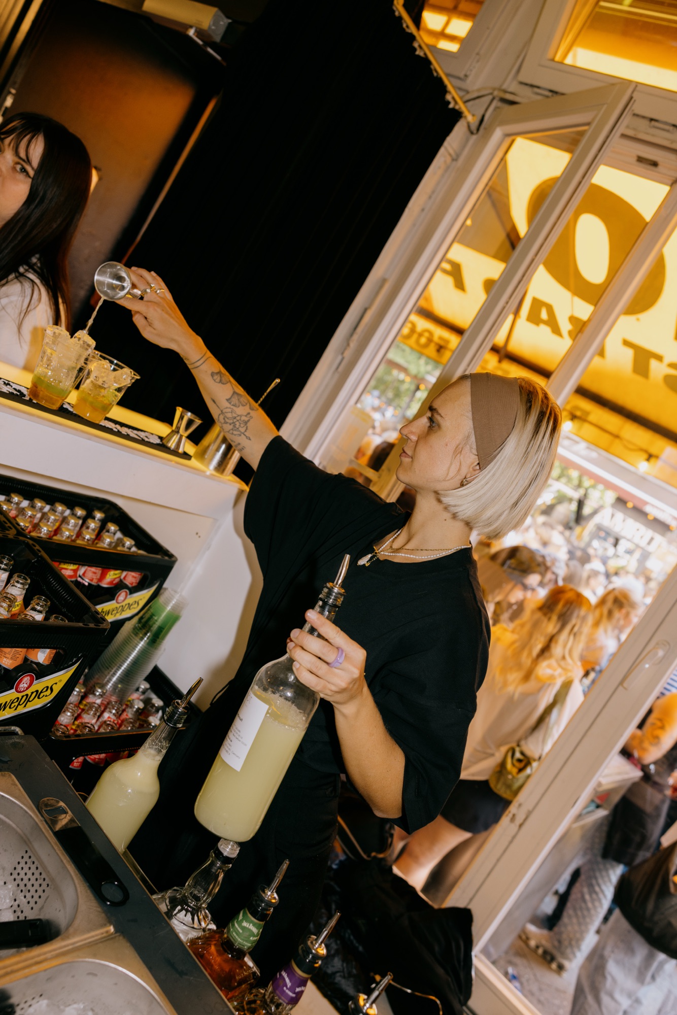 Goldies 1. Mai Fest – Blonde Barkeeperin bereitet Cocktails mit Eis an der offenen Bar zu von Kürsat Gürbüz