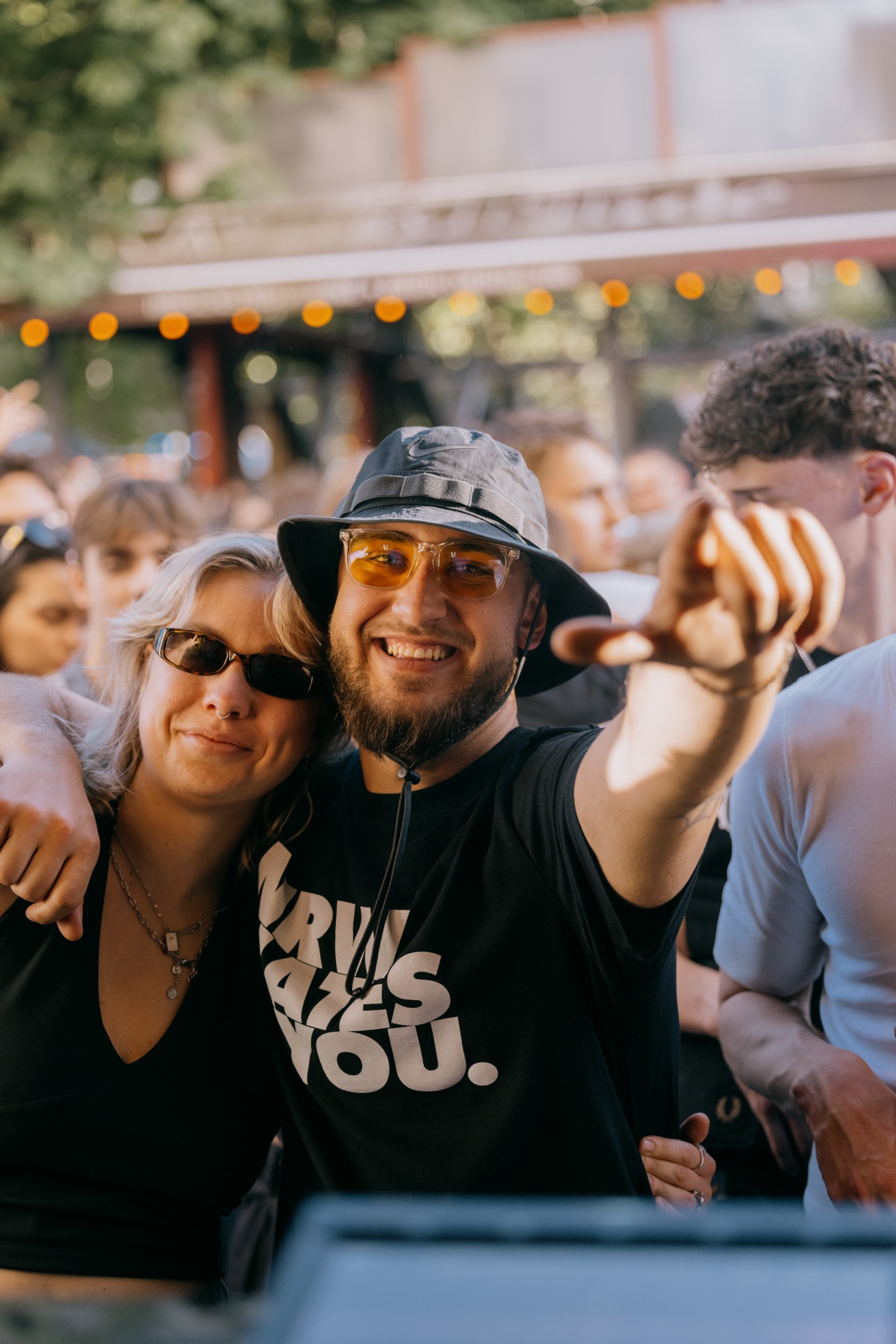 Goldies 1. Mai Fest – Paar mit Bucket Hat zeigt lachend in die Kamera an der DJ-Stage von Kürsat Gürbüz