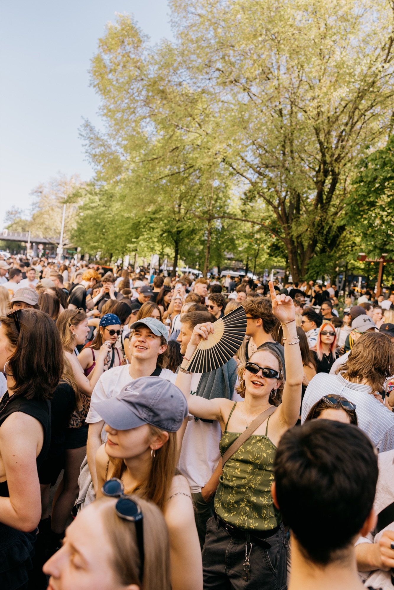 Goldies 1. Mai Fest – Feiernde Gästin mit Fächer und Sonnenbrille in der sonnigen Menge von Kürsat Gürbüz