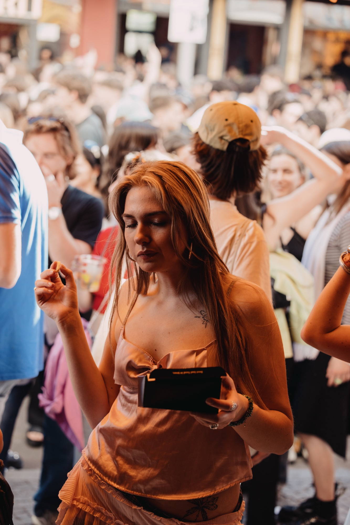 Goldies 1. Mai Fest – Gästin im rosa Satintop isst Pommes Frites im Straßengetümmel von Kürsat Gürbüz