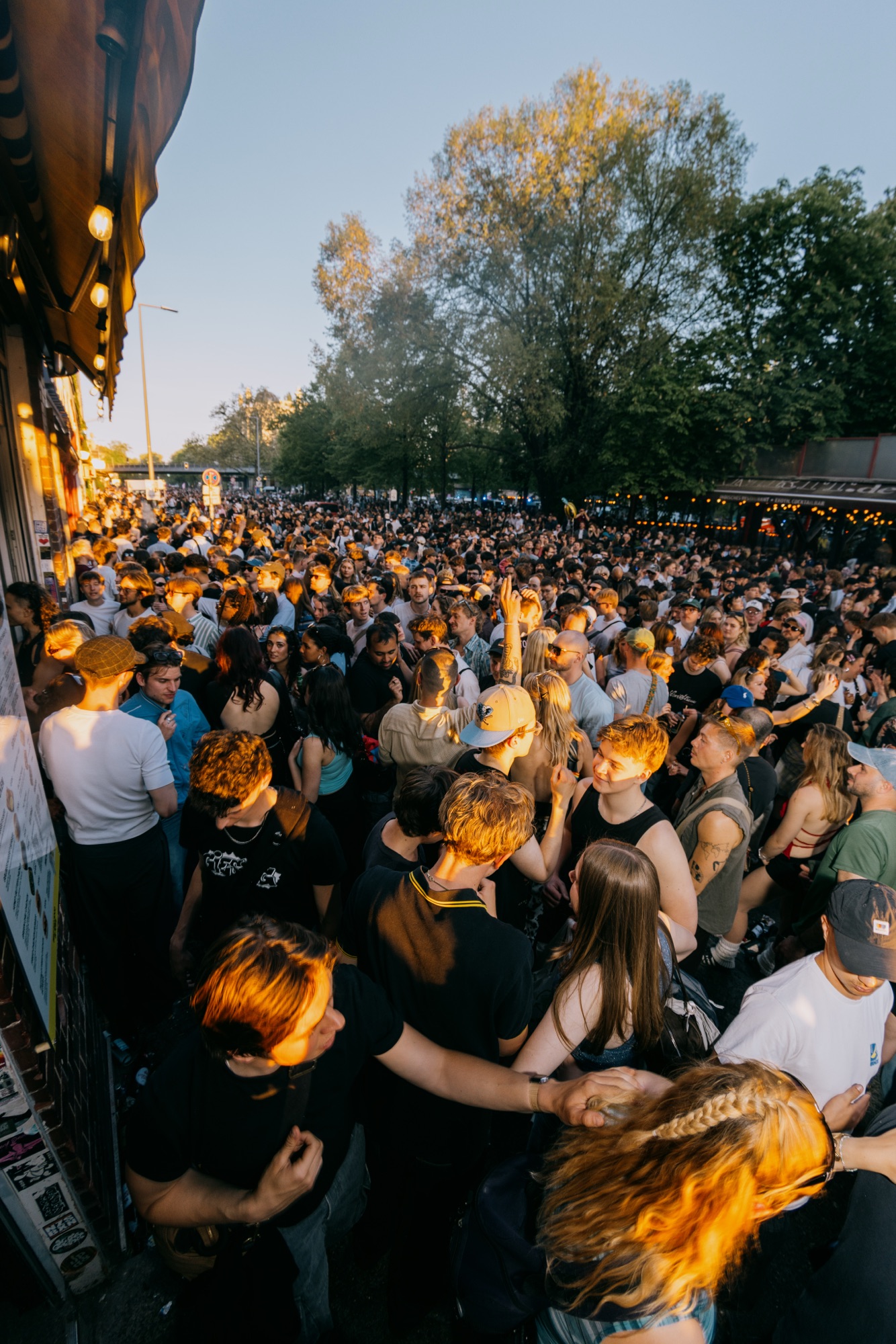 Goldies 1. Mai Fest – Spektakuläre Vogelperspektive über die dicht gedrängte Straßenfest-Menge im warmen Abendlicht von Kürsat Gürbüz