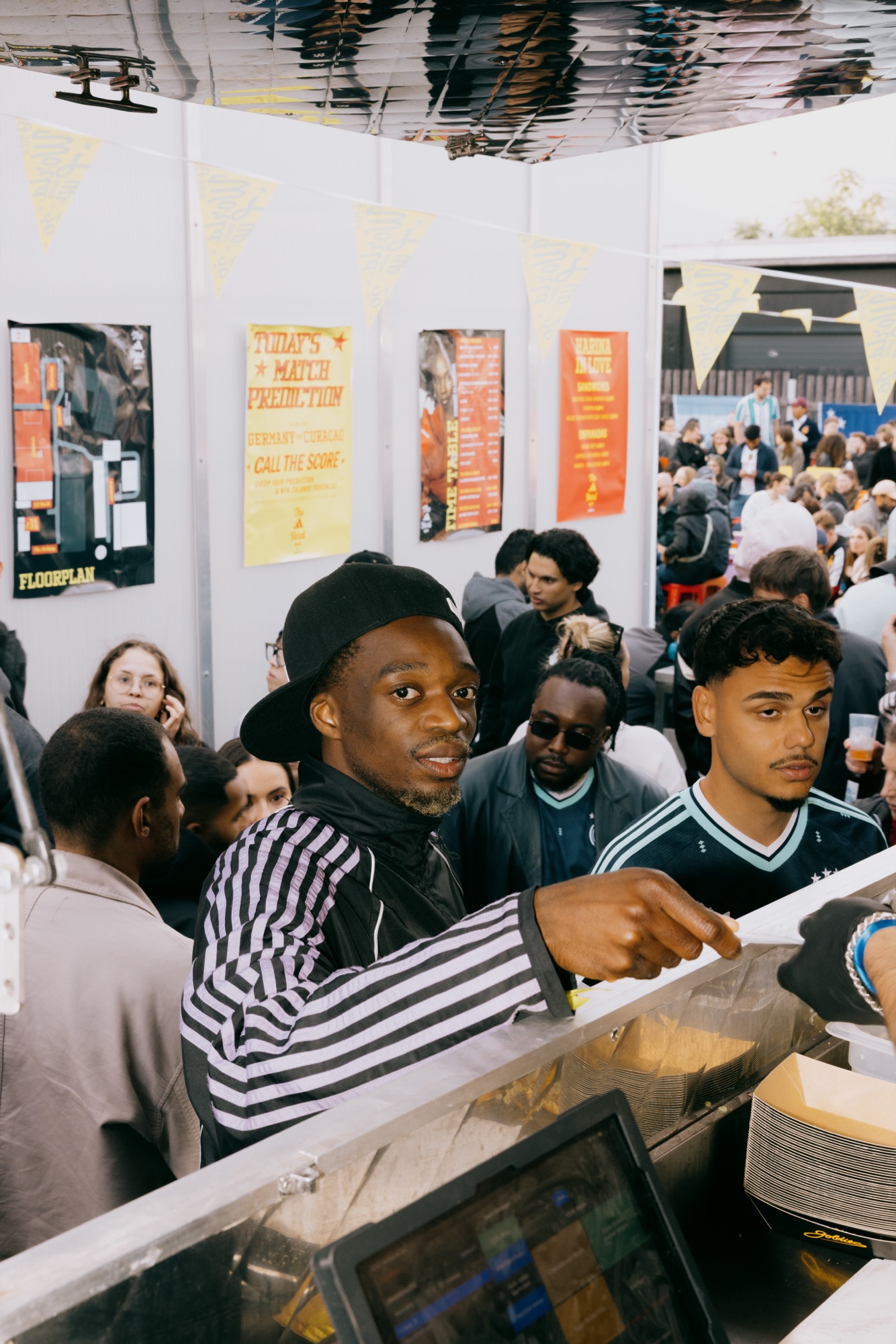 Goldies × Adidas Sportsbase – Gast bestellt am Foodtruck vor Postern von Kürsat Gürbüz