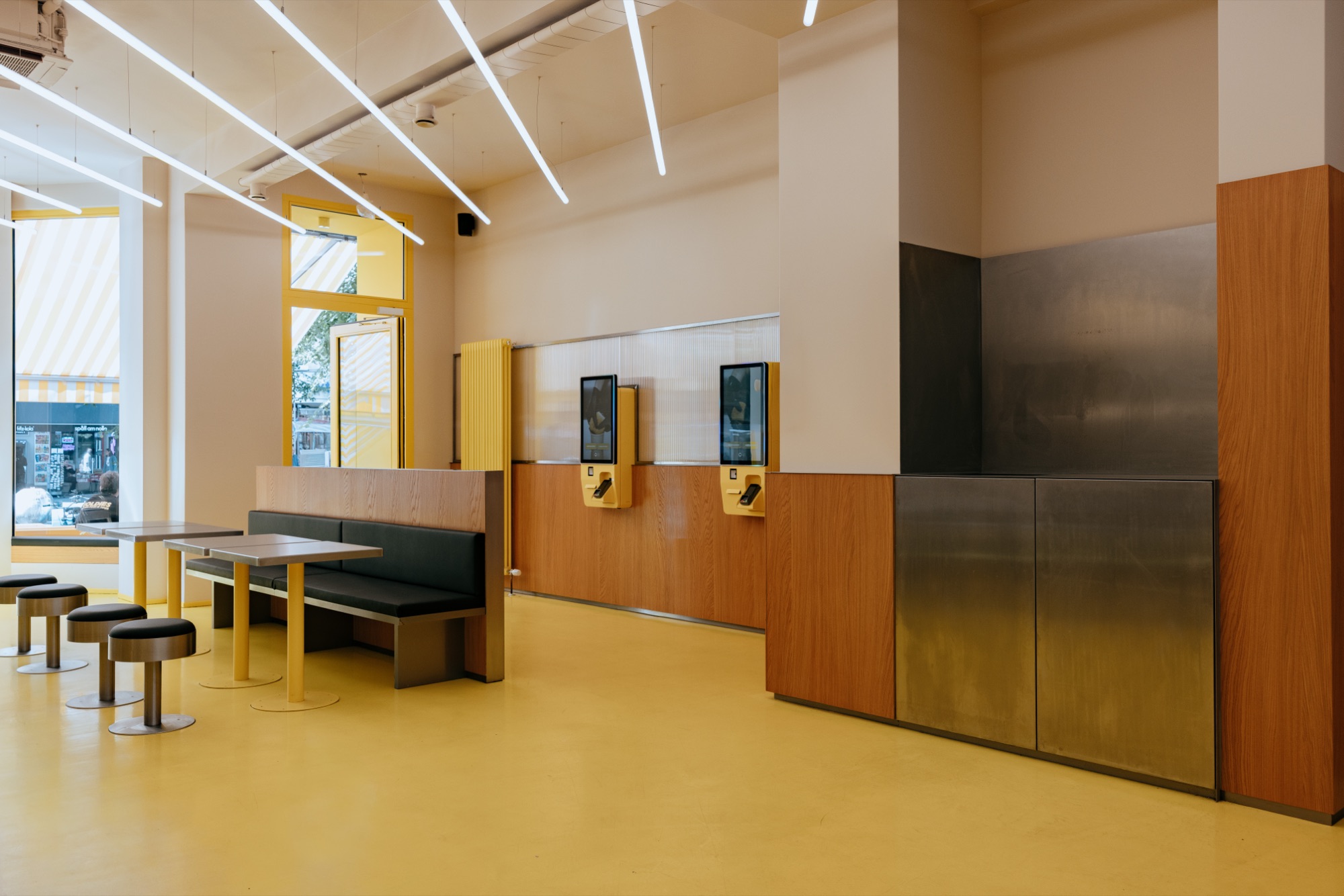 Goldies Schöneberg – Digitale Self-Order Terminals an der holzvertäfelten Wand im hellen Gastraum von Kürsat Gürbüz
