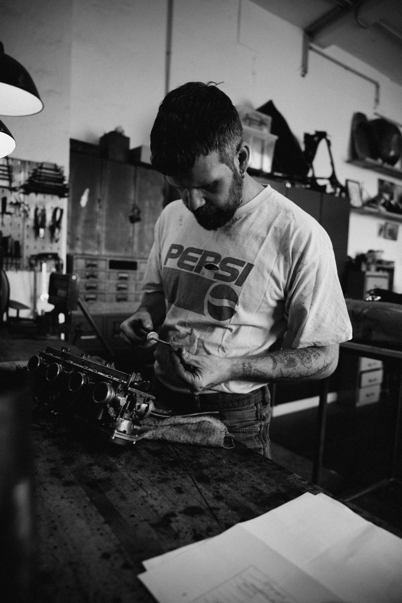 IconicBikes Berlin – Mechaniker Porträt bei Vergaser-Arbeiten in Schwarzweiß