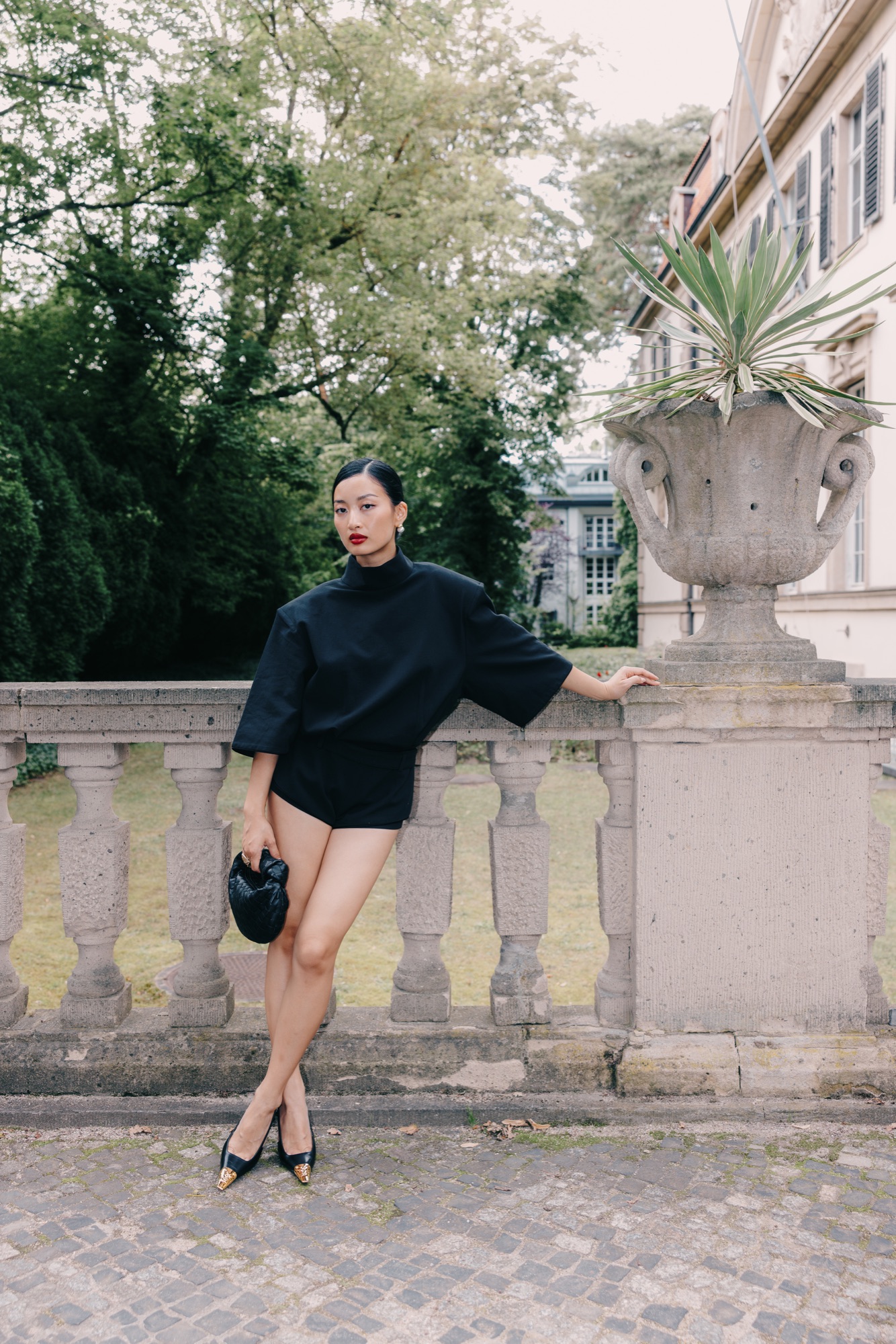 Thanya x PRADA – Ganzkörper-Look mit Prada Handtasche vor klassizistischer Schlossfassade