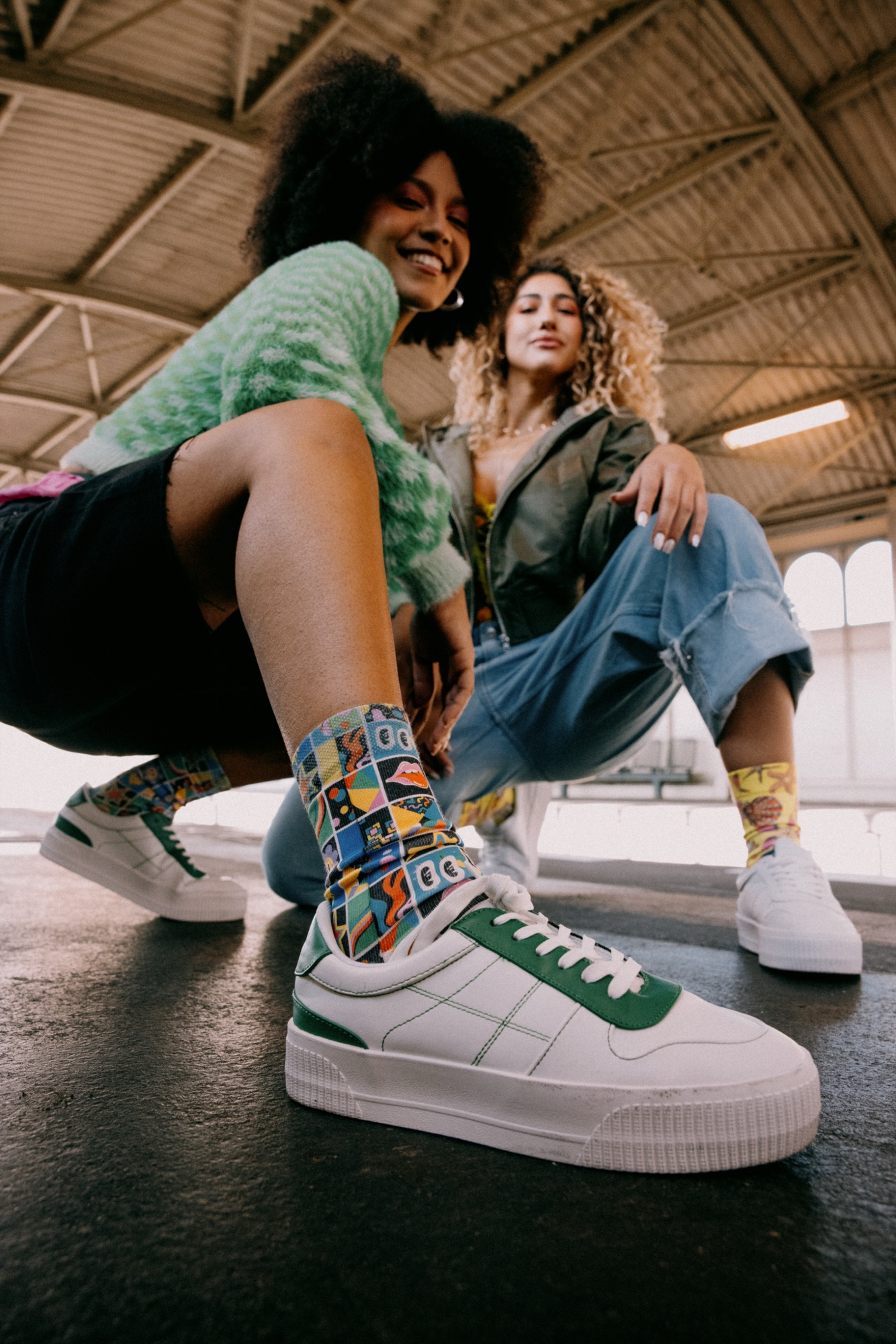 Wiggle Steps – Low-Angle Detailaufnahme bunter Grafik-Socken im Sneaker auf Bahnhofsboden von Kürsat Gürbüz