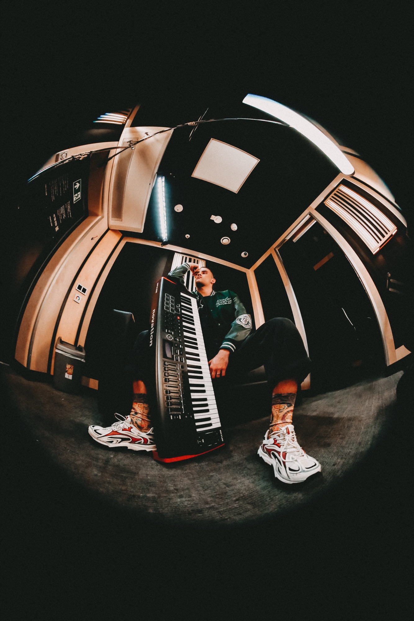 Wiggle Steps – Fisheye-Perspektive mit Synthesizer und Sneakers in Telefonkabine von Kürsat Gürbüz